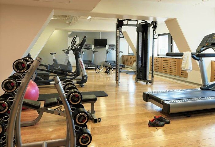 Scandic Copenhagen's gym, a gay-friendly hotel. Treadmills, weights, and elliptical machines on a wood floor. Pet-friendly hotel fitness.