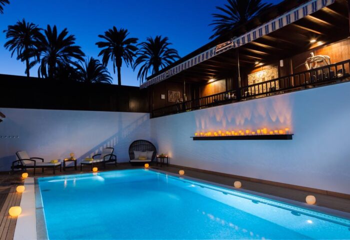 Seaside Grand Hotel Residencia Gran Lujo pool at dusk. Gay-friendly hotel with luxury amenities, romantic lighting, and palm trees.