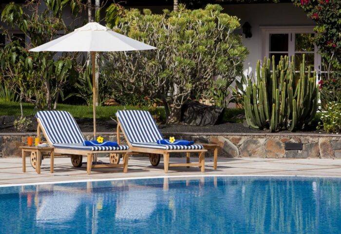 Seaside Grand Hotel Residencia Gran Lujo: Poolside relaxation with striped loungers, umbrella. Gay-friendly hotel in Gran Canaria.