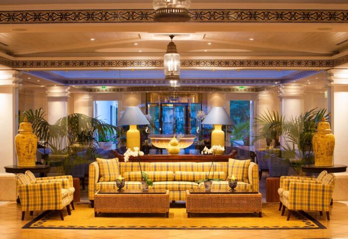 Lobby of Seaside Grand Hotel Residencia Gran Lujo, a gay-friendly hotel. Yellow plaid furniture, lamps, and plants create a luxurious ambiance.