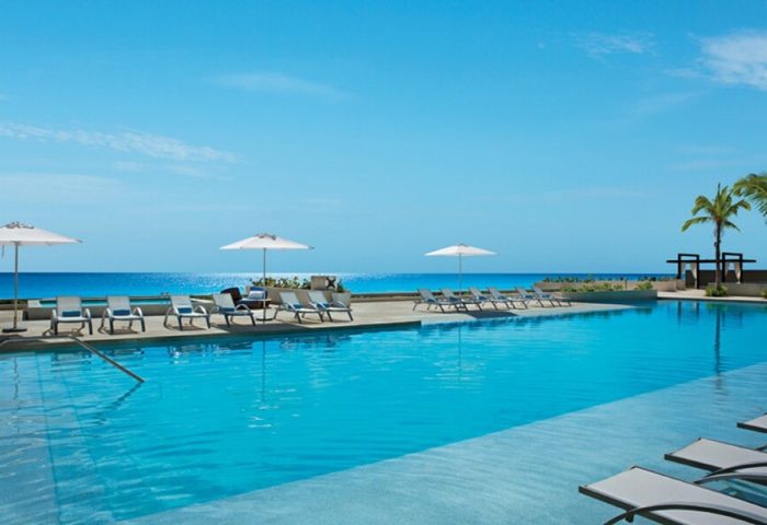 Secrets The Vine Cancun Resort & Spa pool view. All-inclusive, adults-only, gay-friendly hotel. Ocean view, lounge chairs, and umbrellas.