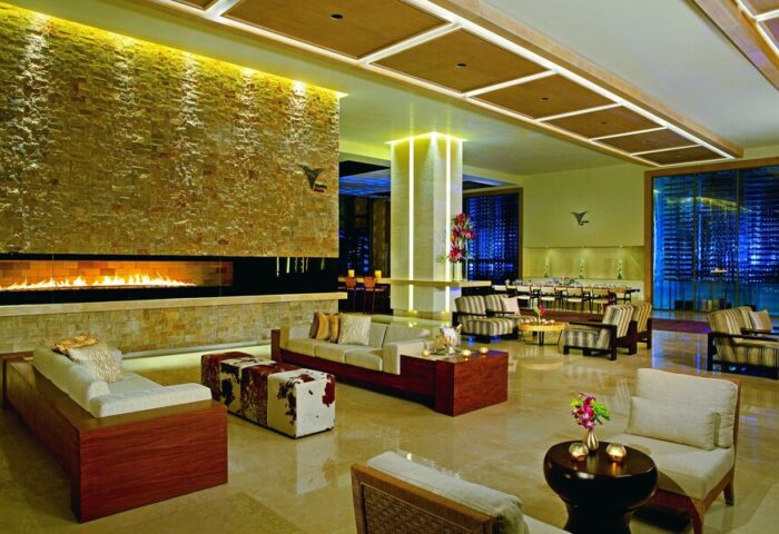 Secrets The Vine Cancun Resort & Spa lobby. Gay-friendly, all-inclusive, adults-only hotel interior with fireplace and seating area.