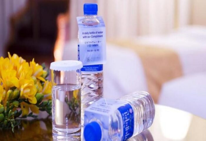 Bottled water and a glass on a table with yellow flowers at the Sejong Hotel Seoul Myeongdong, a gay-friendly hotel in Seoul, South Korea.