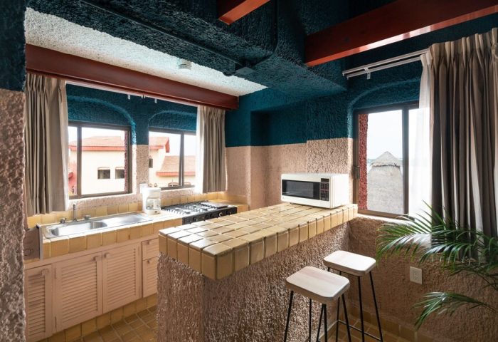Kitchen area at Selina Cancun Laguna Hotel Zone, a gay-friendly hotel. View of the sink, stove, microwave, and stools. Great for gay travel.