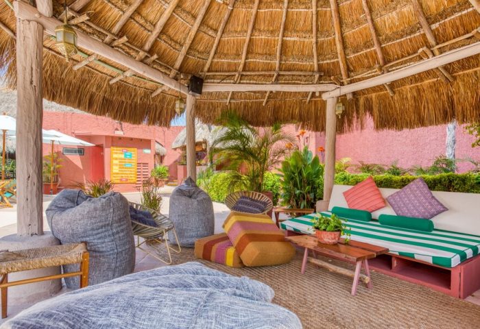 Selina Cancun Laguna Hotel Zone chill area. Gay-friendly hotel with thatched roof, bean bags, and comfy seating in Cancun's Hotel Zone.