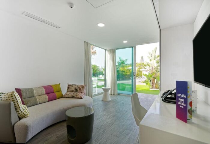 Seven Hotel & Wellness gay men only: Stylish room interior with curved sofa, garden view. Gay-friendly hotel for gay men's travel.