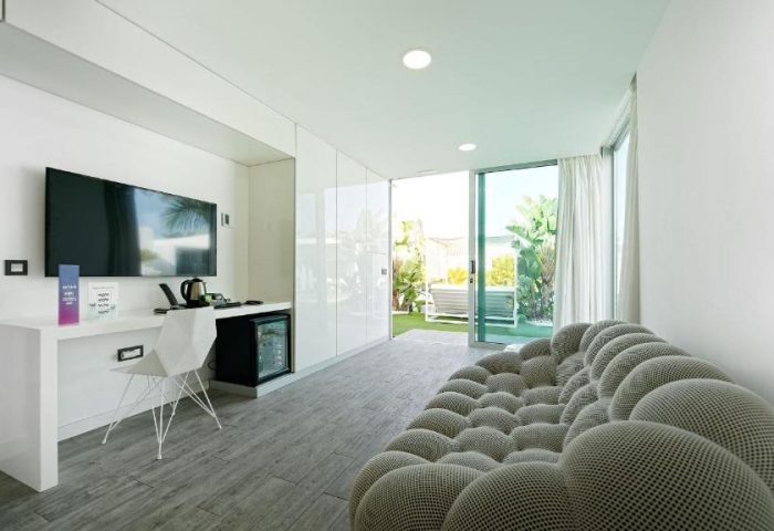Seven Hotel & Wellness, a gay men only hotel. Modern room with TV, desk, and patio view. Gay-friendly hotel interior design.