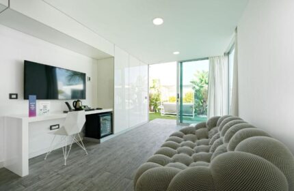 Seven Hotel & Wellness, a gay men only hotel. Modern room with TV, desk, and patio view. Gay-friendly hotel interior design.