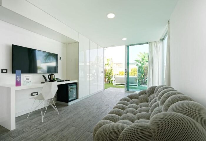 Seven Hotel & Wellness, a gay men only hotel. Modern room with TV, desk, and patio view. Gay-friendly hotel interior design.