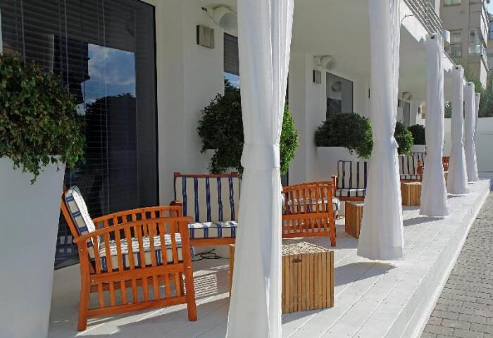 Shalom Hotel & Relax, an Atlas Boutique Hotel. Gay-friendly, pet-friendly hotel patio with white curtains and wood furniture.