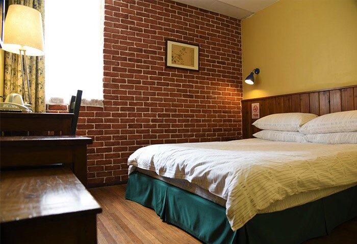 Bedroom at Shanghai Le Tour Traveler's Rest Youth Hostel, a gay-friendly hotel with brick wall, desk, and bed. Bailan Youth Hostel.