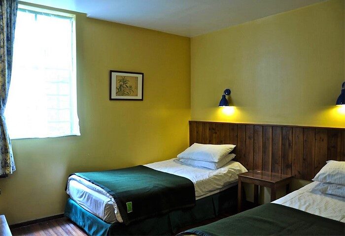 Shanghai Le Tour Traveler's Rest Youth Hostel room. Gay-friendly hotel with twin beds, wood headboard, and bedside lamps. Budget travel.
