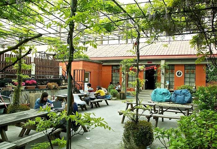 Shanghai Le Tour Traveler's Rest Youth Hostel courtyard. Gay-friendly hotel with outdoor seating, greenery, and relaxed atmosphere. Bailan hostel.