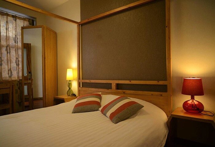 Bedroom at Shanghai Rock & Wood International Youth Hostel, a gay-friendly hotel. Bed with striped pillows and bedside lamps.