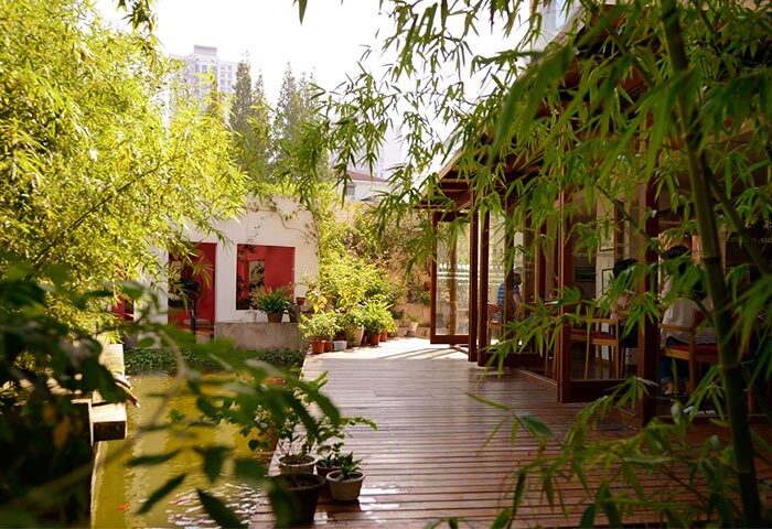 Shanghai Rock & Wood International Youth Hostel's exterior. Gay-friendly hotel with bamboo, plants, and a wooden deck. Relaxing outdoor space.