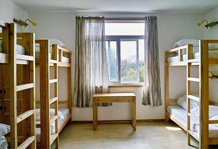 Dorm room at Shanghai Rock & Wood International Youth Hostel. Gay-friendly hotel with bunk beds, desk, and window. Ideal for budget travelers.