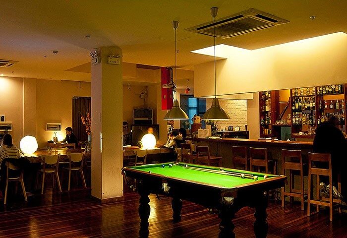 Shanghai Rock & Wood International Youth Hostel's common area with a pool table, bar, and seating. Gay-friendly hotel in Shanghai.
