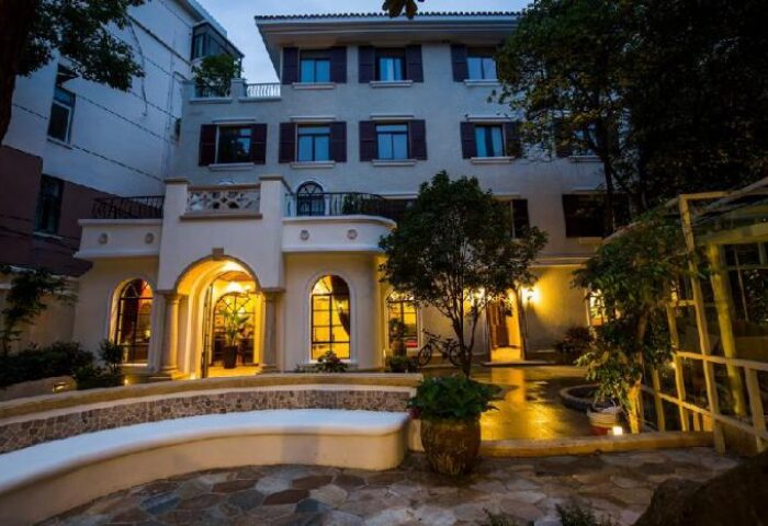 Shanghai Soho Garden Hotel exterior view. Gay-friendly hotel with a garden, stone bench, arched windows, and warm lighting. Great for gay travelers.