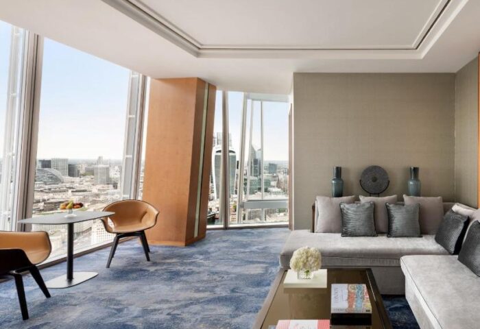 Shangri-La Hotel At The Shard suite interior view. Gay-friendly hotel room with city view, sofa, and table. Luxury travel for gay men.
