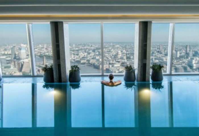 Shangri-La Hotel At The Shard gay-friendly pool. Woman relaxing in the pool with London skyline view. Gay travel luxury hotel.