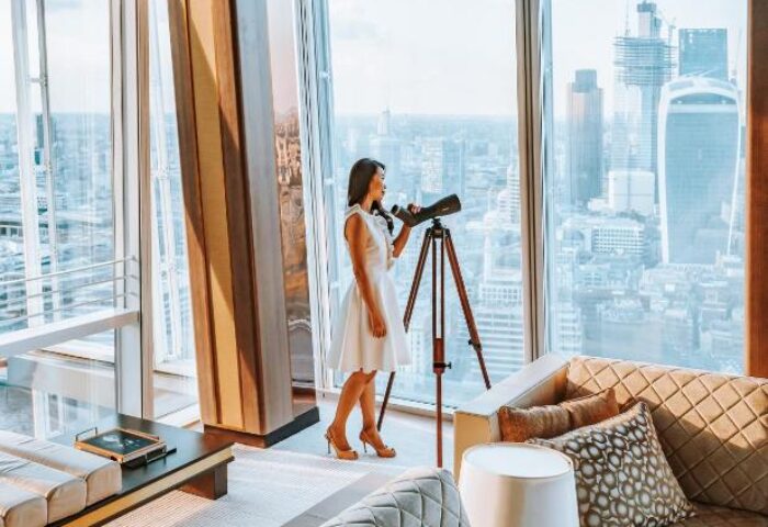 Shangri-La Hotel At The Shard: Woman with telescope enjoying city views. Gay-friendly hotel with luxury accommodations for discerning travelers.