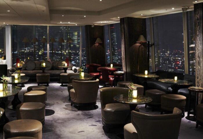 Gay-friendly Shangri-La Hotel At The Shard lounge. Night view of London from the bar. Stylish seating, tables, and city lights.