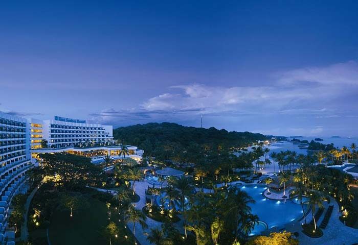 Shangri-La's Rasa Sentosa Resort & Spa, a gay-friendly hotel. Aerial view of the pool, gardens, and hotel at dusk, perfect for gay travel.
