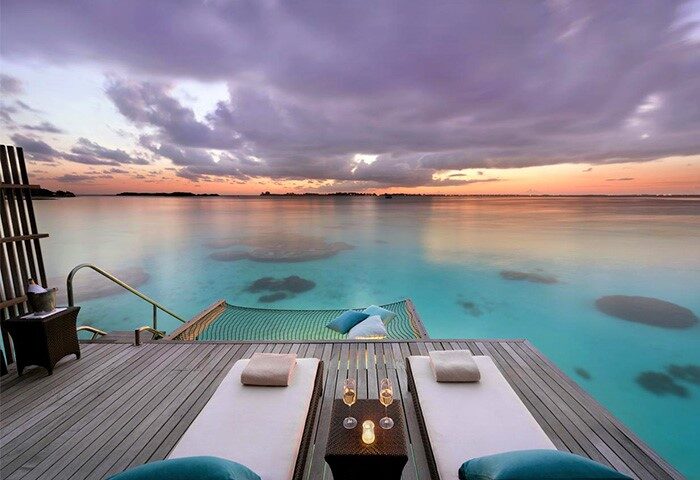 Shangri-La's Villingili Resort & Spa, a gay-friendly hotel. Overwater bungalow deck with lounge chairs, hammock, and sunset view. Maldives luxury.