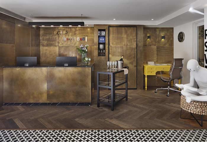Shenkin Hotel's gay-friendly lobby. Reception desk, bar cart with champagne, yellow desk, and modern decor. A stylish Tel Aviv hotel.