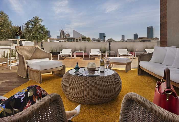 Shenkin Hotel's gay-friendly rooftop terrace. Wicker chairs, sunbeds, and city views. Perfect for gay travel and relaxation.