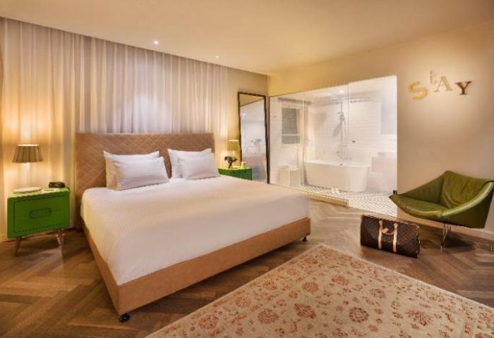 Shenkin Hotel's gay-friendly room: bed, bathroom, green chair, & rug. This hotel offers a comfortable stay for gay men travelers.