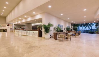 Lobby at Sheraton Buganvilias Resort & Convention Center, a gay-friendly hotel. Reception desk, seating area, and view of palm trees.