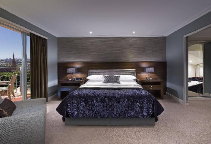 Sheraton Grand Sydney Hyde Park hotel room. Gay-friendly hotel with balcony view. Luxury bedroom interior at Sydney's Hyde Park hotel.