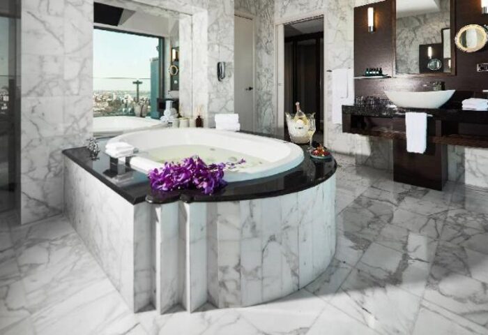 Luxurious bathroom at Sheraton Grand Sydney Hyde Park, a gay-friendly hotel. Marble tub, city view, champagne. Upscale travel for gay men.