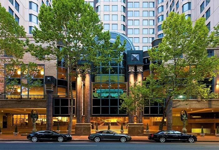 Sheraton Grand Sydney Hyde Park entrance. Gay-friendly hotel with luxury cars parked outside. Upscale travel for gay men in Sydney.