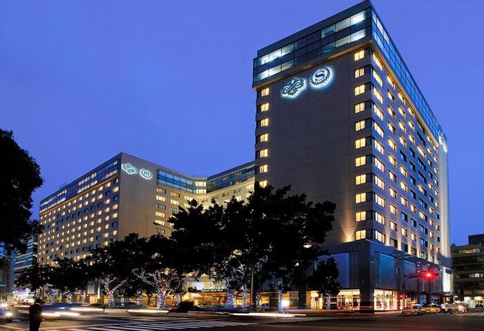 Night view of the Sheraton Grand Taipei Hotel, a gay-friendly hotel in Taipei. The hotel's illuminated logo is visible at the top.