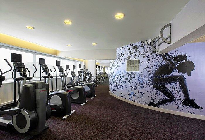 Sheraton Grand Taipei Hotel's gym. Cardio machines line the room with a graphic mural. A gay-friendly hotel for your Taiwan travels.
