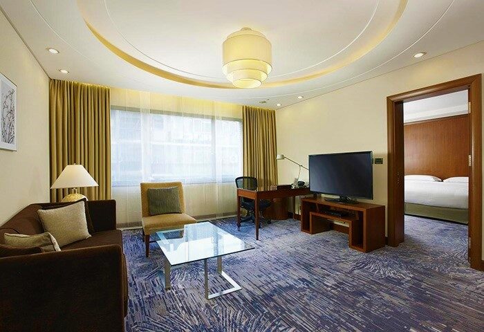 Sheraton Grand Taipei Hotel suite living area. Gay-friendly hotel with modern decor, desk, TV, and bedroom view. Taipei travel advice.