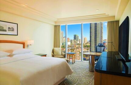 Sheraton Manila Bay gay-friendly hotel room. City view from window, desk, chair, bed. Modern design, comfortable stay in Manila.