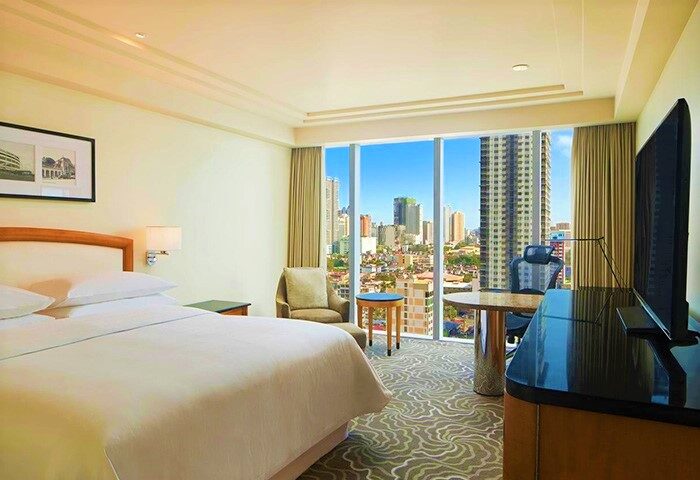 Sheraton Manila Bay gay-friendly hotel room. City view from window, desk, chair, bed. Modern design, comfortable stay in Manila.