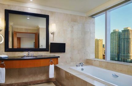 Bathroom at Gay-Friendly Sheraton Manila Bay Hotel. Features a tub with a city view, a large mirror, and modern fixtures. Luxury travel.