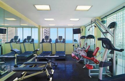 Sheraton Manila Bay gay-friendly hotel gym. Treadmills and weight machines face windows with a city and ocean view. Fitness center.