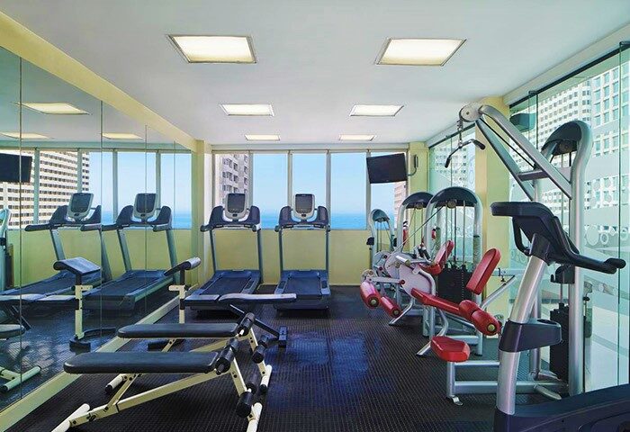 Sheraton Manila Bay gay-friendly hotel gym. Treadmills and weight machines face windows with a city and ocean view. Fitness center.