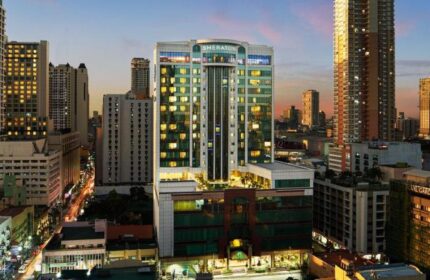Sheraton Manila Bay, a gay-friendly hotel. Exterior view of the hotel at dusk, showcasing its modern architecture and the surrounding cityscape.