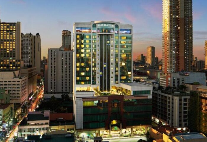 Sheraton Manila Bay, a gay-friendly hotel. Exterior view of the hotel at dusk, showcasing its modern architecture and the surrounding cityscape.