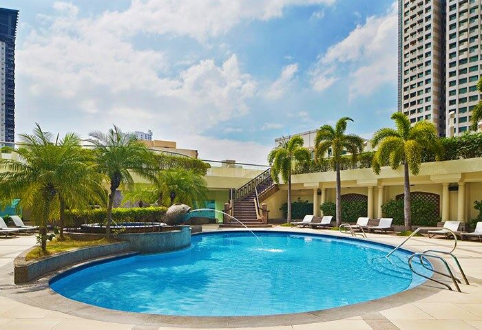 Sheraton Manila Bay gay-friendly hotel pool. Relax in style at this luxury Manila hotel. Palm trees, lounge chairs, and city views.