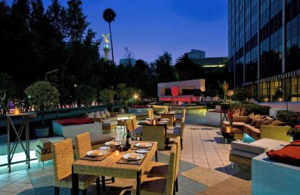 Outdoor dining at the gay-friendly Sheraton Mexico City Maria Isabel Hotel. Tables and lounge seating on the patio at dusk.