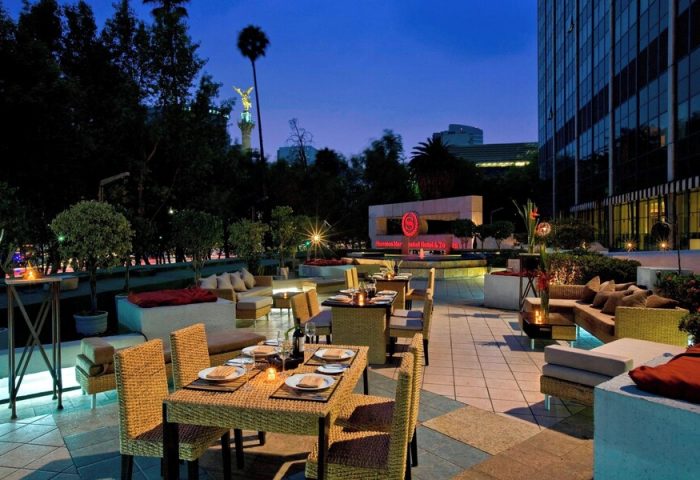 Outdoor dining at the gay-friendly Sheraton Mexico City Maria Isabel Hotel. Tables and lounge seating on the patio at dusk.
