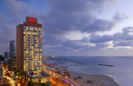Sheraton Tel Aviv Hotel at dusk. Gay-friendly, pet-friendly hotel on the beach. View of the city skyline and Mediterranean Sea.
