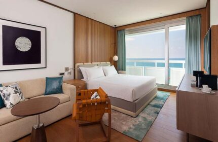 Sheraton Tel Aviv Hotel gay-friendly room. Pet-friendly hotel with sea view, modern decor, sofa, and woven leather chair. Perfect for gay travel.